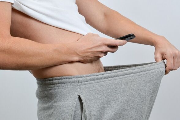 Ένας άντρας κοιτάζει ένα διευρυμένο πέος μέσα από το παντελόνι του